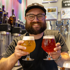 Man holding two glasses of beer in a bar setting
