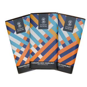 Three Stewart Brewing chocolate bars with a colorful geometric pattern of blue, orange, and white stripes on a black background, arranged in a fan shape on a white background.