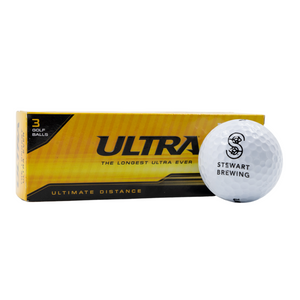 A pack of three Stewart Brewing branded white golf balls with a yellow and black box. The golf balls are labeled 'ULTRA' and promote 'Ultimate Distance'.